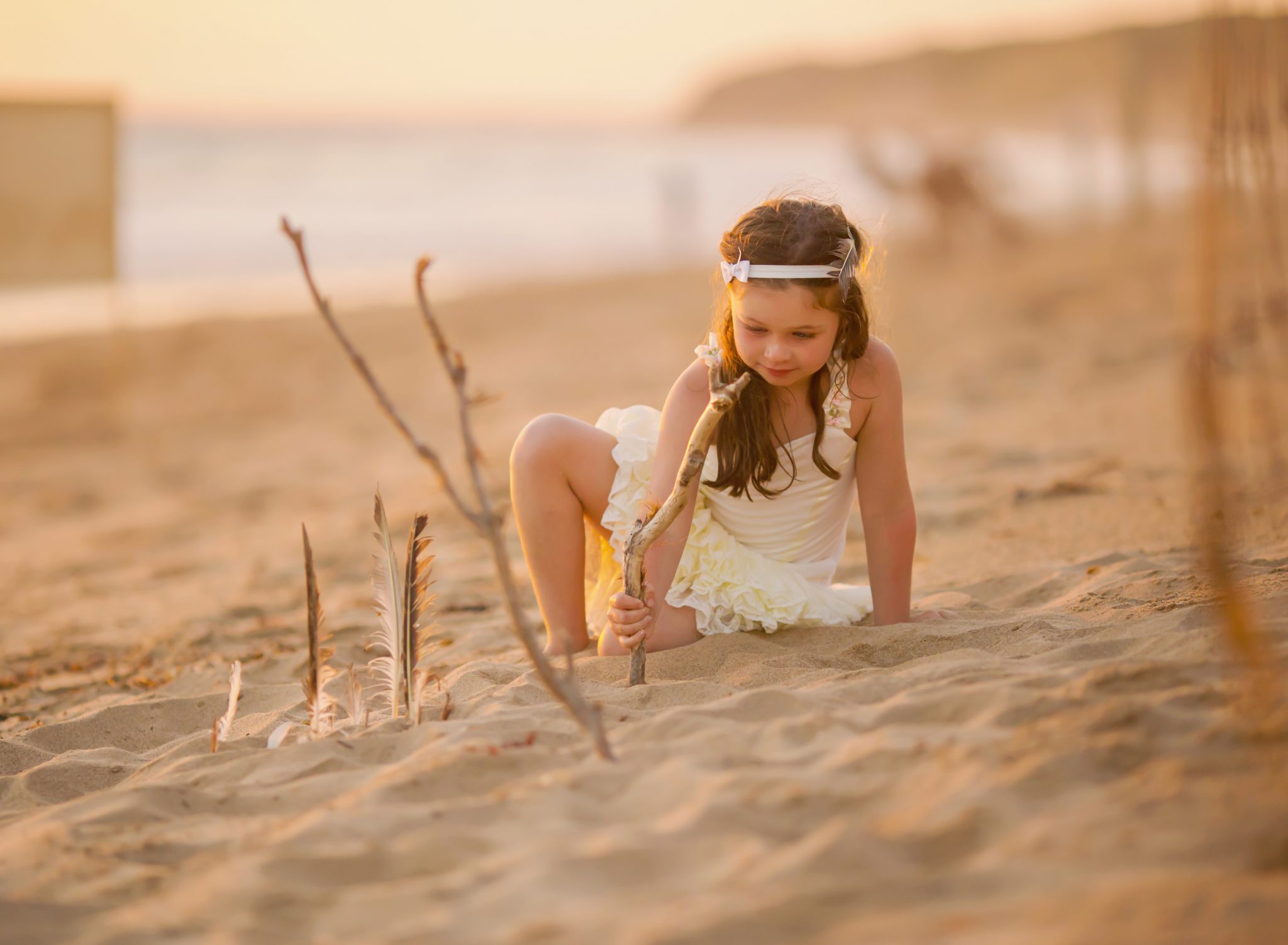 Young girl posing at sunset by the sand castle she built 